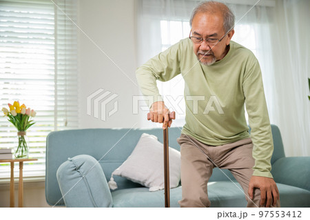 Asian Old man with eyeglasses typing to stand up from sofa with walking cane, Elderly suffering from knee pain ache holding handle of cane, senior disabled man holding walking stick at home Asian Old man with eyeglasses typing to stand up from sofa with walking cane, Elderly suffering from knee pain ache holding handle of cane, senior disabled man holding walking stick at home 97553412
