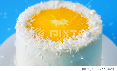 Cake with orange and coconut shavings spinning on a blue background. 97553624