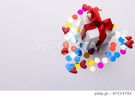 White gift box with red ribbon on heart shape of confetti, on white background with copy space White gift box with red ribbon on heart shape of confetti, on white background with copy space 97554793
