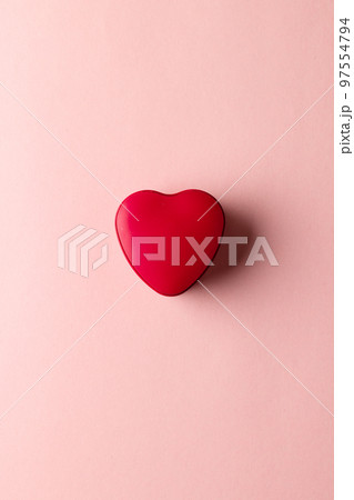 Overhead vertical image of red heart shaped box on pale pink background with copy space 97554794