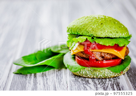 Front view of green homemade burger with marble beef with veggies, greenery on wooden table Front view of green homemade burger with marble beef with veggies, greenery on wooden table 97555325