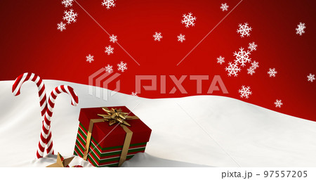 Image of snow falling over candy canes and christmas present on red background 97557205