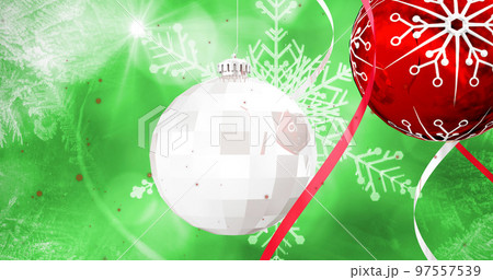 Image of snow falling over christmas bauble decorations on green background 97557539