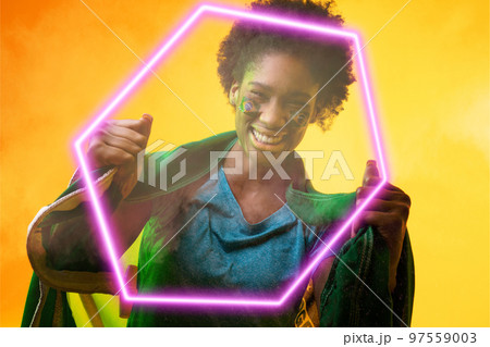 Hexagon neon over cheerful african american female fan with flag during soccer match Hexagon neon over cheerful african american female fan with flag during soccer match 97559003