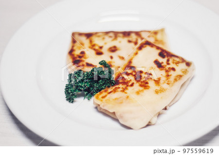 thin pancakes with meat filling and a sprig of parsley on a white plate 97559619