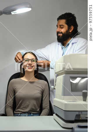 Happy caucasian woman testing new glasses with optometrist in optical store. Eyesight and vision concept Happy caucasian woman testing new glasses with optometrist in optical store. Eyesight and vision concept 97559751