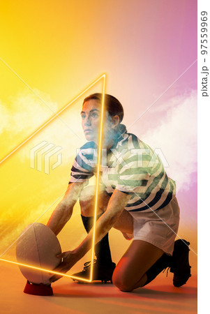 Illuminated triangle over caucasian female player placing rugby ball on stand amidst smoke Illuminated triangle over caucasian female player placing rugby ball on stand amidst smoke 97559969