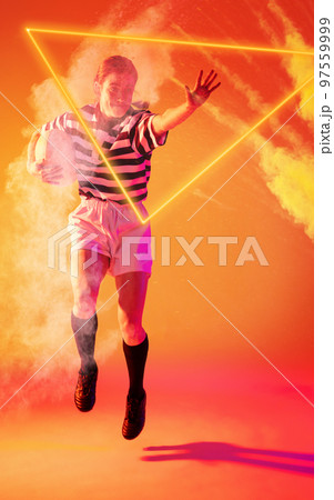 Caucasian woman jumping with ball by illuminated triangle and smoke on orange background Caucasian woman jumping with ball by illuminated triangle and smoke on orange background 97559999