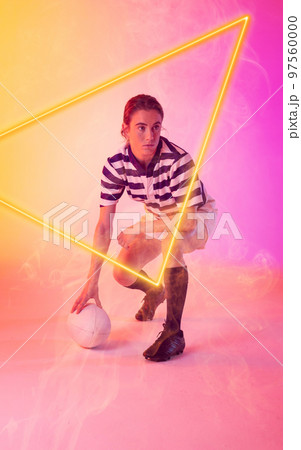Caucasian female rugby player with ball crouching by illuminated triangle on gradient background 97560000
