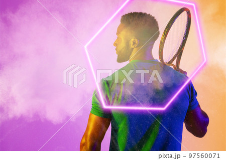 Rear view of african american male player with racket by illuminated hexagon over smoky background Rear view of african american male player with racket by illuminated hexagon over smoky background 97560071