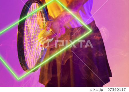 Midsection of african american female tennis player holding racket and ball by illuminated rectangle 97560117
