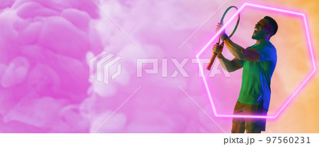 African american male player with racket screaming by illuminated hexagon over smoky background 97560231