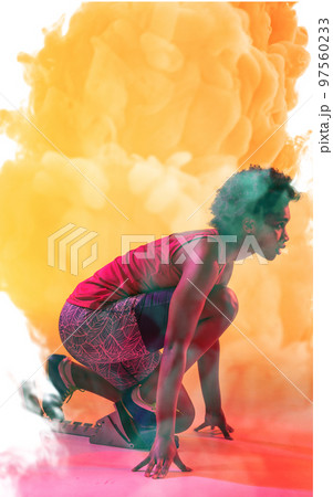 Side view of african american female athlete crouching at starting position on smoky background 97560233