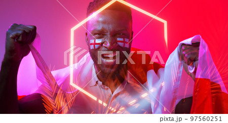 African american male fan with england flag and face paint screaming by hexagon and plants African american male fan with england flag and face paint screaming by hexagon and plants 97560251