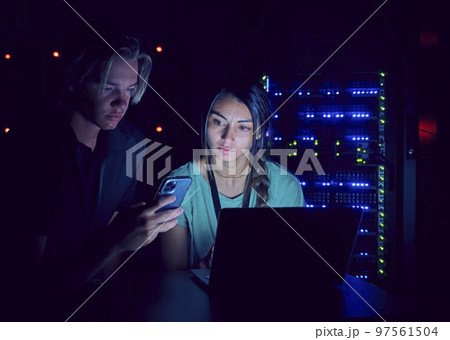 Technicians using laptop and smart phone in server room 97561504