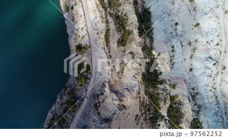 Turquoise water in a mountain forest lake with pine trees. Aerial view of blue lake and green forests. View on the lake between mountain forest. Over crystal clear mountain lake water. Fresh water  97562252