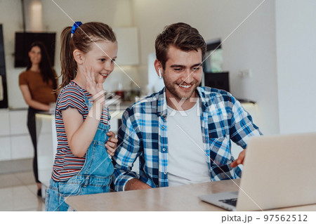 Father and daughter in modern house talking together on laptop with their family during holidays. The life of a modern family 97562512