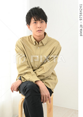 屋内で椅子に座る若い男性ポートレート 97564241