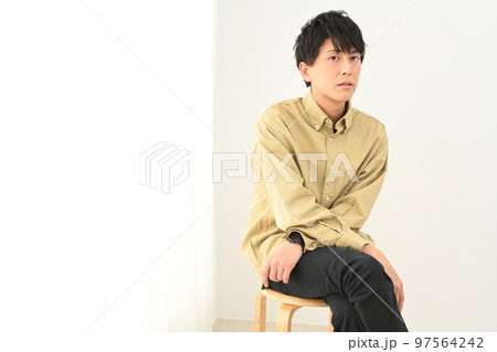 屋内で椅子に座る若い男性ポートレート 97564242