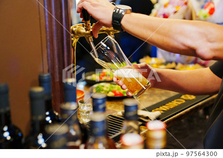 men's hands pour beer into a beer tap glass. men's hands pour beer into a beer tap glass. 97564300