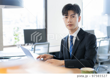 オフィスでスーツでパソコン作業をする若い男性のポートレート 97565527