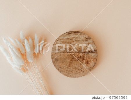 Wood brown round podium and bouquet of dry Lagurus on beige background 97565595