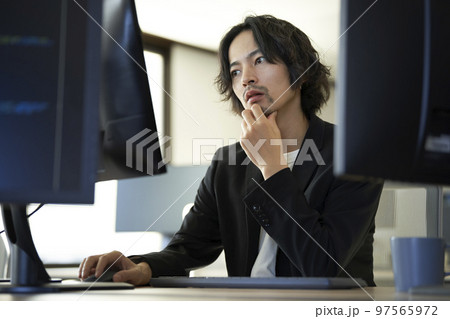 デスクトップパソコンで作業をする30代前半の男性 97565972