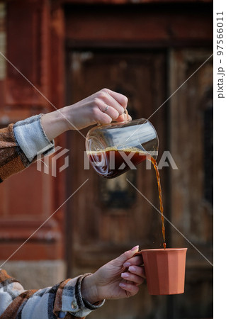 Black coffee is pouring into a cup from glass teapot Black coffee is pouring into a cup from glass teapot 97566011