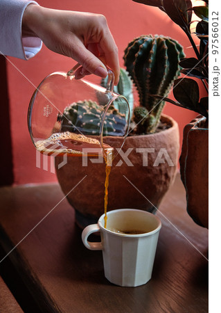 Black coffee is pouring into a cup from glass teapot Black coffee is pouring into a cup from glass teapot 97566012