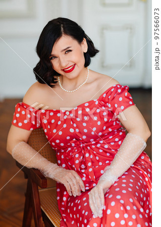 portrait of beautiful and happy brunette in red retro dress and gloved  97566073