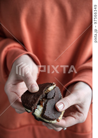 Girl holds broken chocolate cookie. Whoopie pie 97566349
