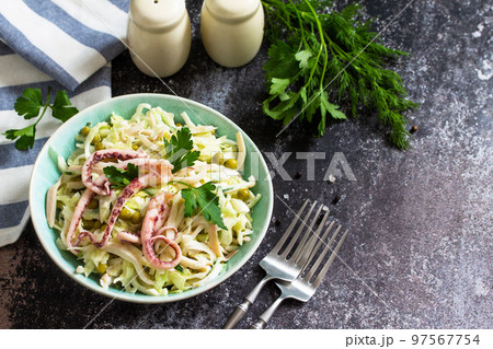 Salad with fresh cabbage, cucumber, green peas and octopus in a bowl on a dark countertop. Copy space. 97567754