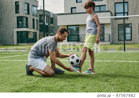 Side view young father teaching son football in outdoor court 97567982