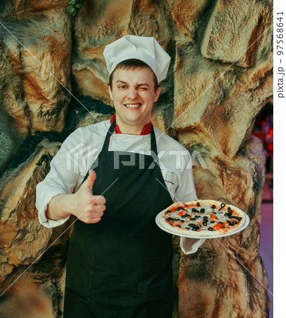 chef holds a large pizza and shows a thumb up 97568641