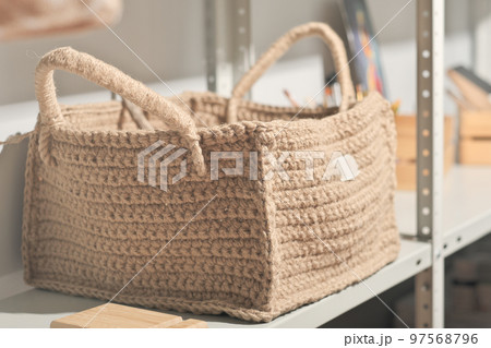 square shape jute knitted basket for natural storage on a shelf. eco knit item, hobby and leisure. natural home interior design. 97568796