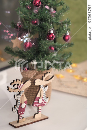 christmas tree decorated with viva magenta colored balls. wooden elks decor in trendy palette of 2023. vertical. holiday house decoration. 97568797
