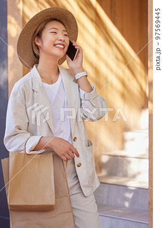 Asian woman, shopping bags or phone call in city for retail networking, urban luxury sales or clothing boutique buying. Smile, happy or fashion customer with gifts on mobile communication technology 97569445
