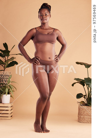 Portrait, body and beauty with a model black woman in studio on a beige background with hands on hips. Health, wellness and underwear with an attractive young plus size female posing for natural care 97569469