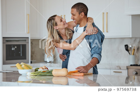 Cooking, love or couple hug in a kitchen with healthy food diet in an interracial relationship or marriage at home. Carrot, vegetables or happy woman hugging romantic partner preparing a dinner meal Cooking, love or couple hug in a kitchen with healthy food diet in an interracial relationship or marriage at home. Carrot, vegetables or happy woman hugging romantic partner preparing a dinner meal 97569738