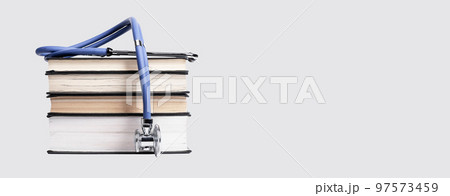 Banner with medical education concept. Books stack with stethoscope. Getting medicine knowledge, study for becoming doctor. Copy space on grey background 97573459