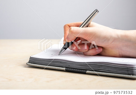 Woman hand closeup taking notes in planner. Female writing with pen information, reminders, schedule in diary. Handwriting. 97573532