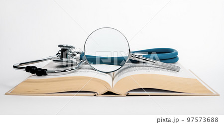 Open book with stethoscope and magnifier. Medical education concept. Conducting research in medicine field. Search of data about illnesses and cure Open book with stethoscope and magnifier. Medical education concept. Conducting research in medicine field. Search of data about illnesses and cure 97573688