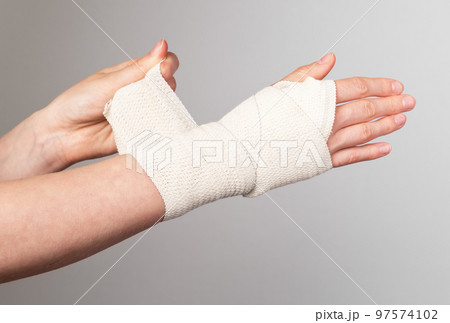 Woman wrapping elastic bandage around painful wrist. Compression wrap. Muscle sprains, strains treatment. Arm trauma. Health care concept. 97574102