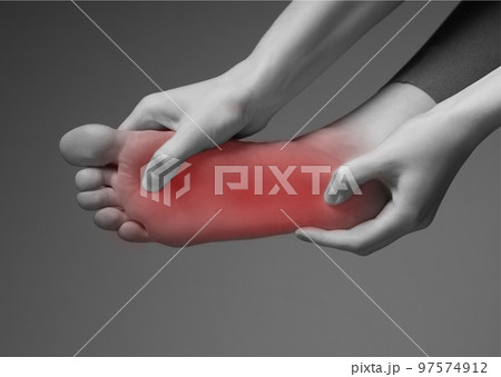 Foot pain. Woman hands holding leg with red point. Black and white. Inflammation, injury, chronic diseases consequences. Health problems concept. 97574912