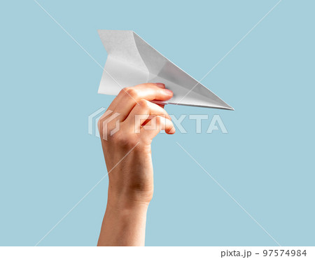 Woman hand holding origami plane on blue background. Flying paper airplane 97574984