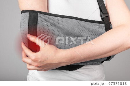 Woman holding painful elbow in sling with red point. Female wearing bandage for supporting arm. Healing process. Fracture, overuse, inflammation consequences. Woman holding painful elbow in sling with red point. Female wearing bandage for supporting arm. Healing process. Fracture, overuse, inflammation consequences. 97575018