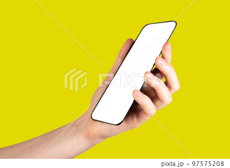 Hand holding phone mockup in angled position on yellow background. Smartphone template. Device for social communication, work, leisure. 97575208