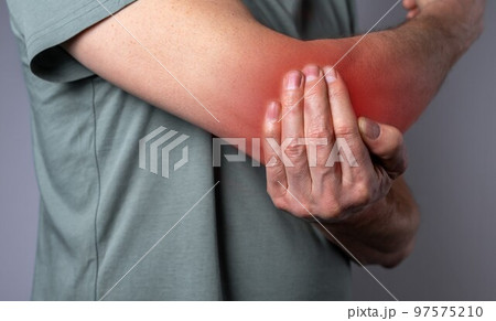 Man suffering from elbow pain and holding painful hand with red point closeup. Hand injury. Health care, joint diseases concept 97575210