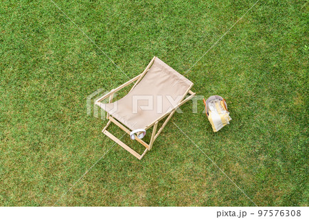 Deck chair, basket for picnic, headphones on the green grass at summer day. Top view, drone, aerial view. 97576308