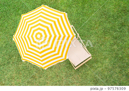 Yellow umbrella with deck chair on the green grass sunbathes at summer day. Top view, drone, aerial view. 97576309